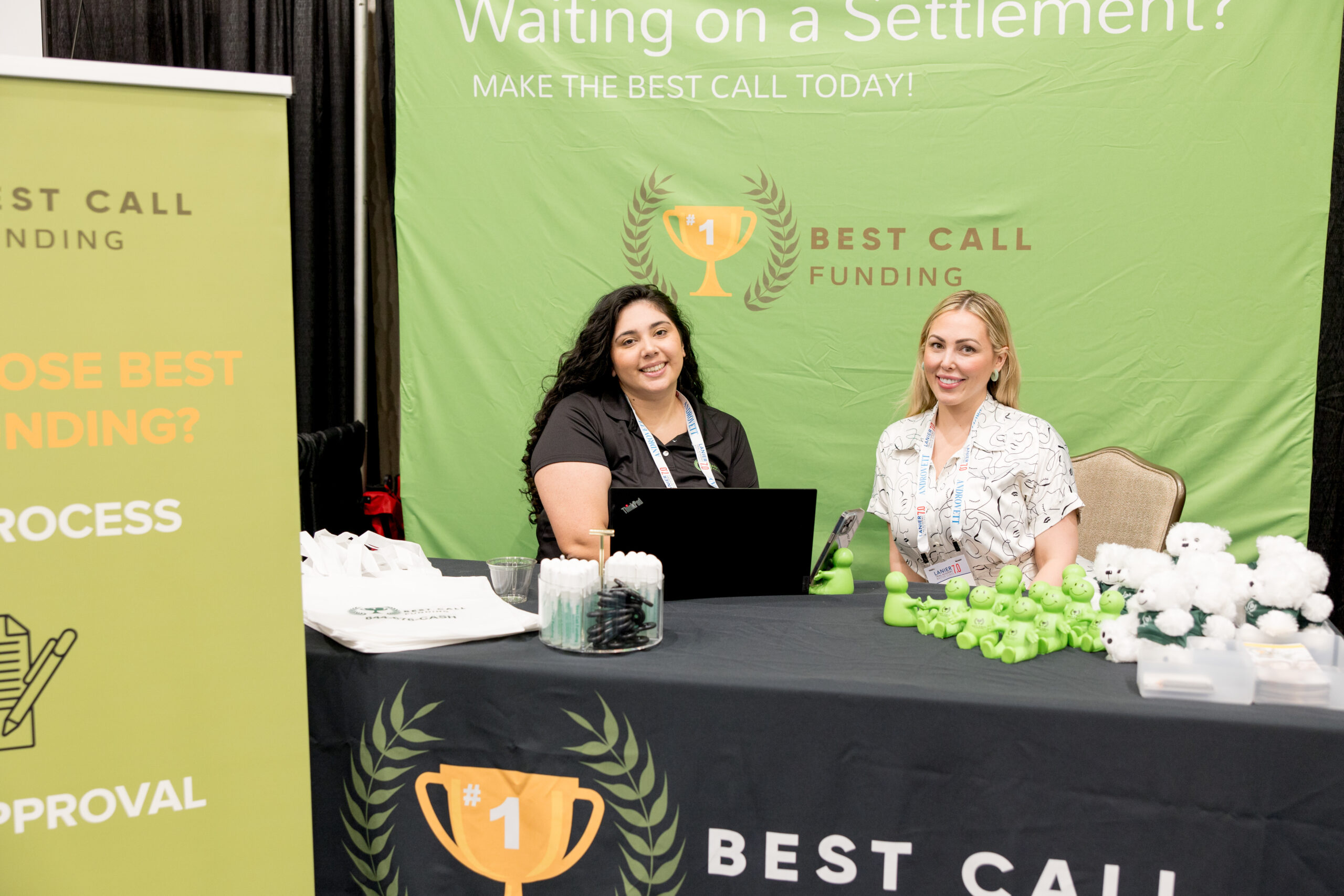 two women sit at a booth together as exhibitors